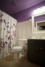 a simple bathroom in purple, creamy and black, with a printed curtain and a black floating vanity