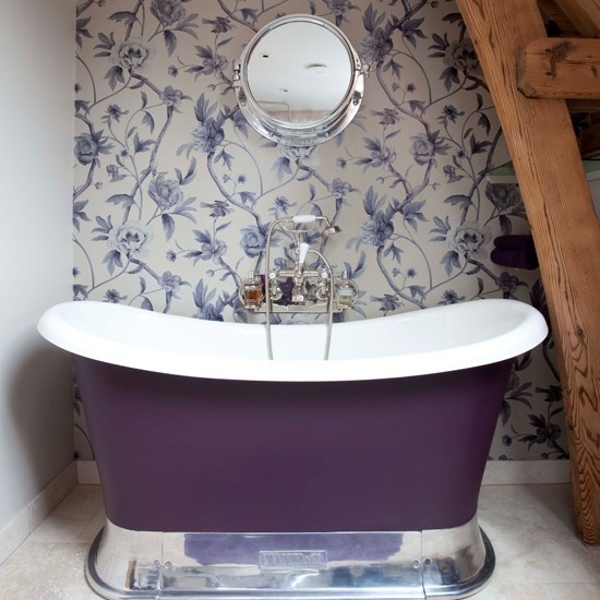 a cozy vintage-inspired bathroom nook with floral wallpaper in purple and lilac and a chic purple bathtub