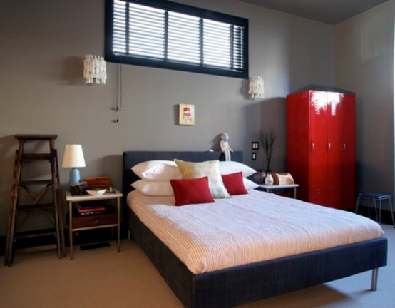 a grey bedroom with a black bed, neutral bedding, matching nightstands, a ladder, a red set of lockers and some stools