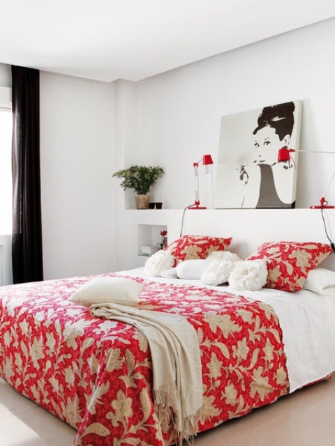 a white bedroom with black curtains, a white bed with red printed bedding, red table lamps and potted plants