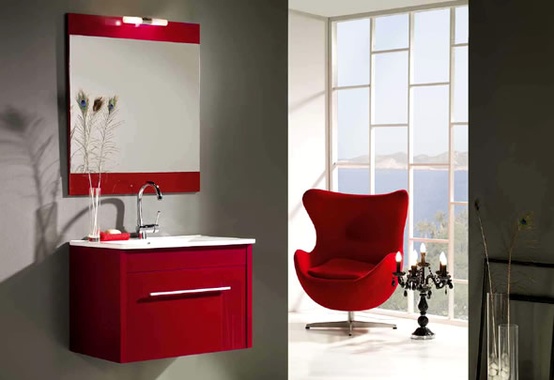 a grey contemporary bathroom finished off with a red mirror, floating vanity and a red chair for a sleek and modern look