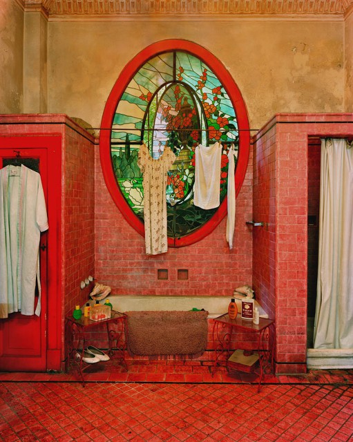 a whimsical bathroom with red tiles and buttercream walls, a mosaic window and a built-in bathtub for a unique look