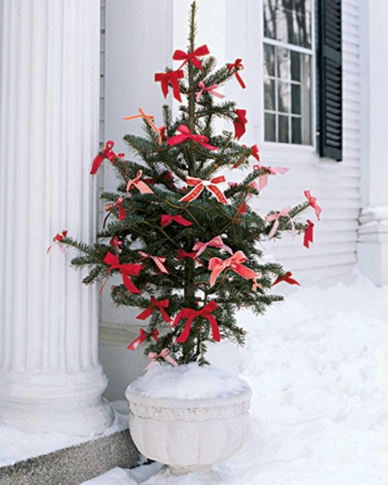 an outdoor Christmas tree decorated with red bows only is a lovely idea for any outdoor space, it looks cool and chic
