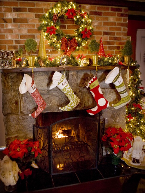 a red, green and gold Christmas space with a wreath over the mantel, a garland with bells on the mantel, green and red stockings and lights is a lovely and cozy space