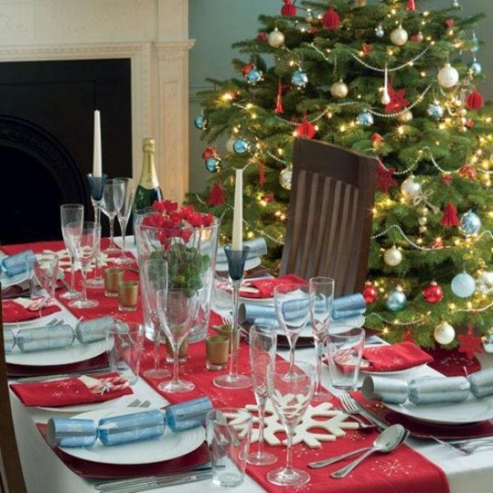 a catchy Christmas dining space decorated in red, light blue and white, with a beautiful Christmas tree and a tablescape done in the same colors and with snowflakes