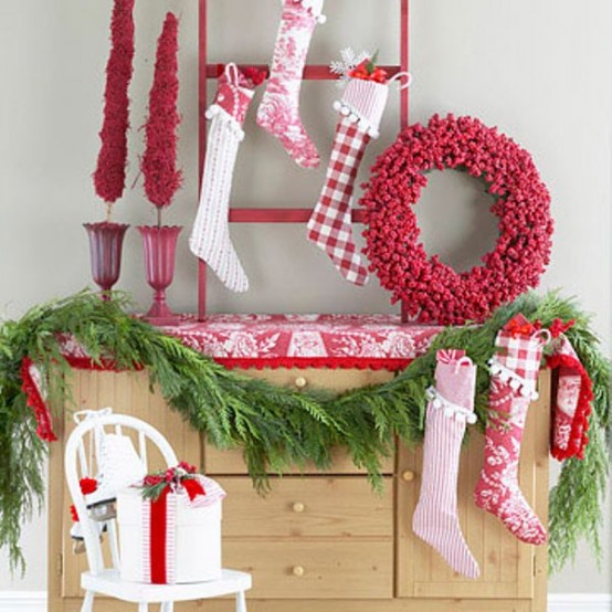 bold red and white Christmas decor with red and white stockings, a red Christmas wreath, an evergreen garland and a gift box with a red ribbon