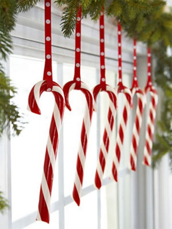 evergreens and red and white candy canes hanging on red loops are cool and lovely Christmas window decor