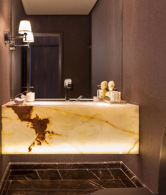 a taupe modern bathroom with a built-in onyx sink slab that is lit up and looks amazing in the space giving it a luxurious feel