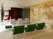 a modern luxurious space with green and grey chairs, with a beige-colored onyx accent wall that makes a statement and adds interest here