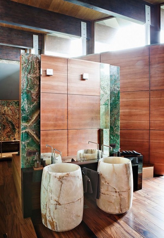 a catchy contemporary bathroom done with stained wood panels, with bold green onyx accents and white onyx free-standing sinks that make the space ultimate