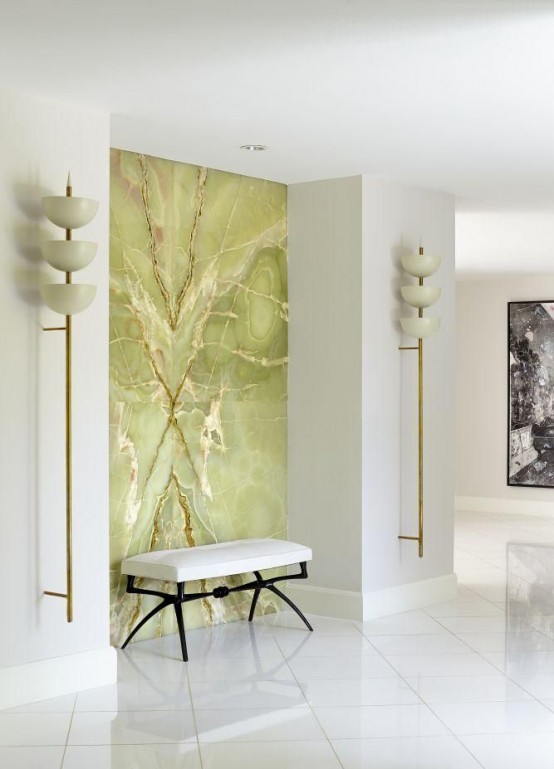 a chic and refined entryway in white with a single green onyx accent wall and a white upholstered bench is a lovely space to be in