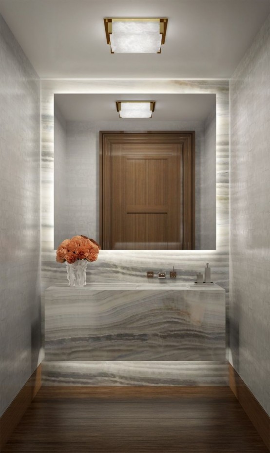 a stylish contemporary bathroom clad with grey onyx, with a lit up accent wall, an onyx vanity and lights over the slab