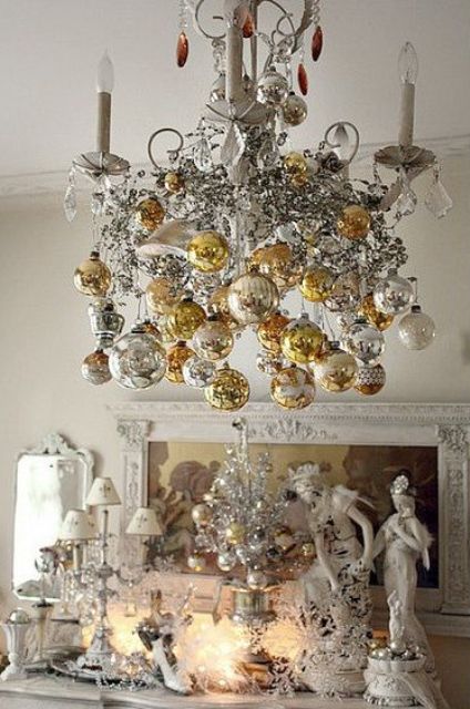 an exquisite candle chandelier with silver, white and gold ornaments hanging down, a tiny silver Christmas tree with bright metallic ornaments
