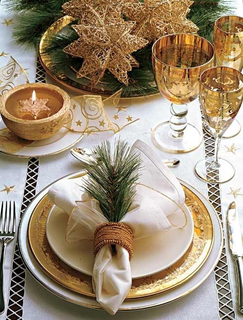 a refined gold and white Christmas tablescape with gold chargers, white porcelain, gold star ribbons, oversized gold wire stars for a centerpiece