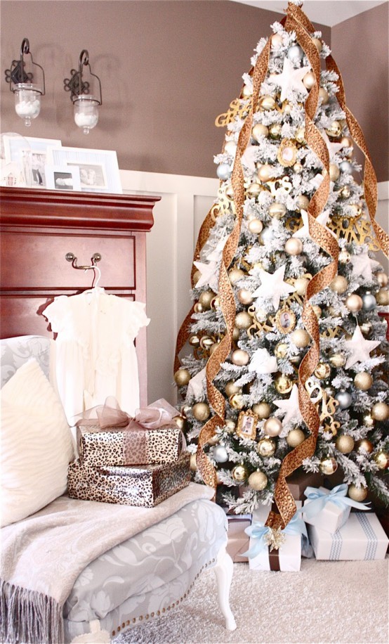 a fabulous flocked Christmas tree with gold and silver baubles, white stars, shiny gold ribbons and a gold star on top is amazing