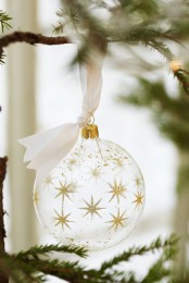 a clear Christmas ornament with gold glitter stars on white silk ribbon is a lovely decoration for the holidays