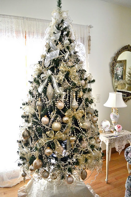 a shiny glam Christmas tree decorated with gold ornaments of various shapes, white bows, pearl beaded garlands is a beautiful idea