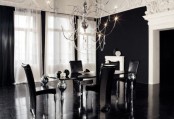 a refined modern black and white dining space with a ling table on catchy legs, black chairs, black curtains and walls, a catchy crystal chandelier