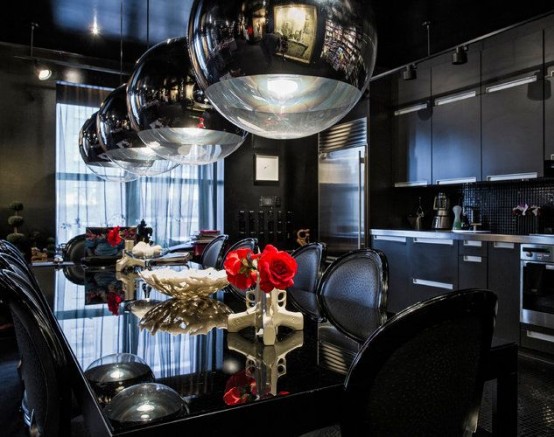 a modern Gothic eat-in kitchen with sleek black cabinetry, a black backsplash, a black glass table and leather chairs, catchy bubble lamps and bone vases