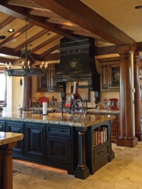 a Gothic kitchen with heavy wooden cabinets and a dark wooden kitchen island, a large vintage hood and a beautiful chandelier over the island