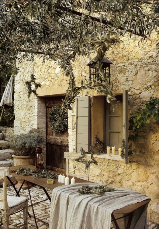 a warm-colored rustic Mediterranean terrace with a wooden table, a whitewashed chair, lots of potted greenery and trees around
