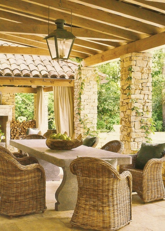 a pretty Provence terrace with a roof, a stone table, woven chairs, greenery and fresh fruit is an awesome place