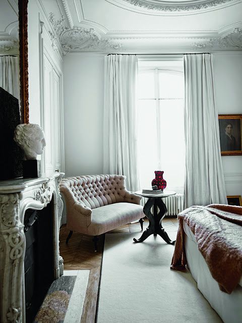 a French chic bedroom with gorgeous molding on the ceiling, with a refined non-working fireplace, chic furniture and white and bron textiles