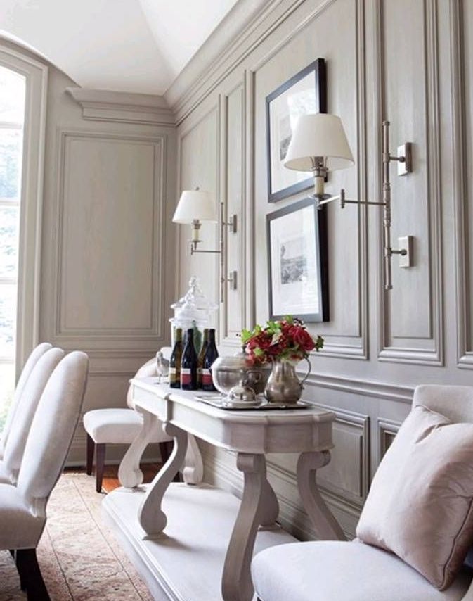 a refined neutral space with grey walls with molding, white and whitewashed furniture, artworks and chic wall sconces is amazing