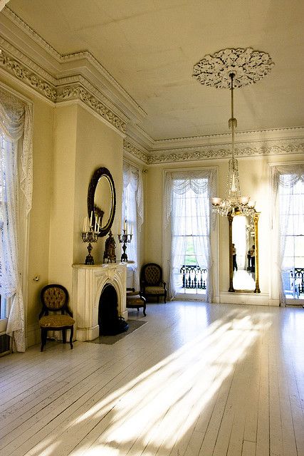 a neutral living room with molding on the ceiling, with a ceiling medallion and a planked floor, a fireplace with a refined touch and some vintage items is wow