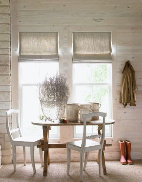 a rustic dining space made more chic with whitewashed wooden walls, Roman shades, chic furniture is welcoming and cozy