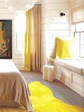 a bright farmhouse bedroom with whitewashed walls, neutral furniture and bright yellow accents plus an artwork is wow