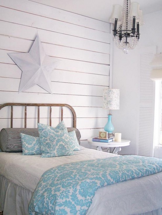 a coastal bedroom with a whitewashed wall, a vintage bed, a crystal chandelier, a whitewashed star on the wall