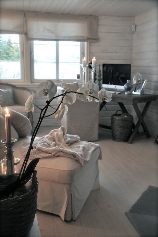 a rustic vintage living room with whitewashed wooden walls, white furniture, a trestle desk and baskets plus decor and candles