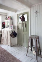 whitewashed beadboard walls, a neutral storage unit, a metal stool and a green door for a vintage farmhouse space