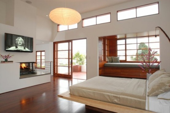 a neutral Japanese-style zen bedroom with a wooden bed, a daybed by the windowsill, a built-in fireplace and paper lamps