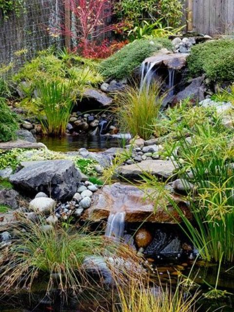 un elegante patio delantero japonés con cascadas, rocas, guijarros, vegetación y musgo alrededor para una sensación relajante y calmante