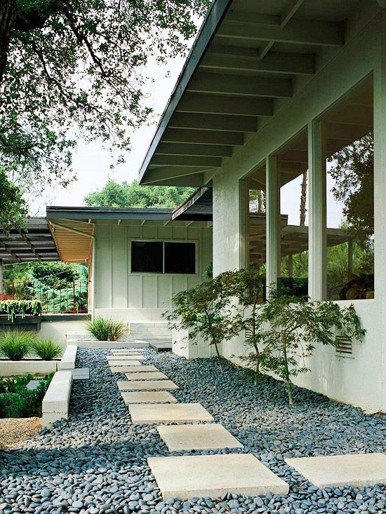 a minimalist Japanese front yard with pebbles and large tiles, with greenery and small trees is amazing