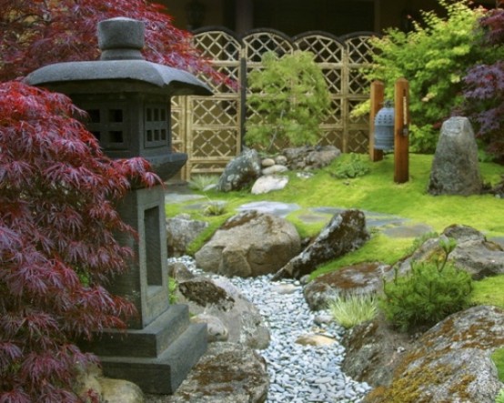 green grass, pebbles, rocks, red maples, a stone lantern and a large bell create a very beautiful and zen-like look