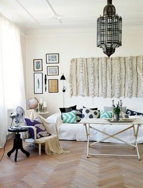 a neutral Moroccan living room with traditional lamps and a Moroccna wedding blanket on the wall