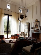 a neutral Moroccan living room spruced up with carved furniture, a cluster of pendant lamps and a mosaic fireplace