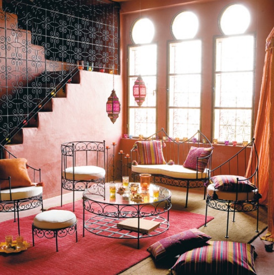 a super colorful living room with wrought furniture, bright textiles and colorful pendant lamps