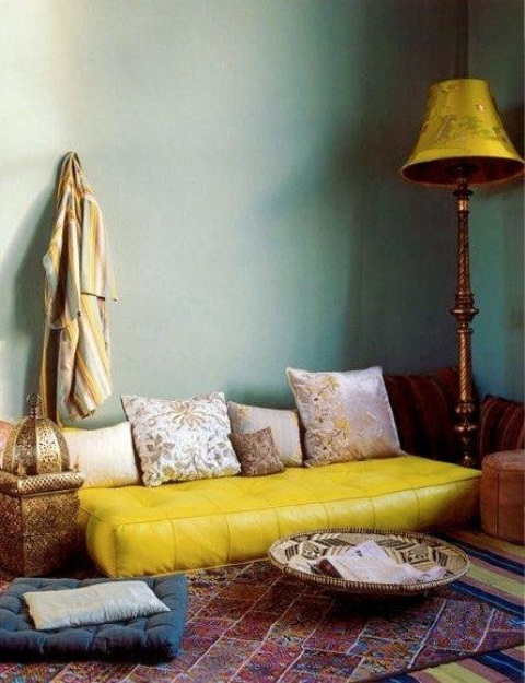 a colorful Moroccan living room with green walls, a yellow sofa and bold rugs and a traditional lantern