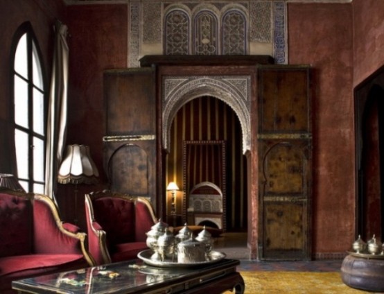 a moody Moroccan living room with beautiful doors, a decorative window, and traditional teaware