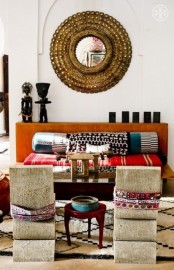 a neutral living room with a colorful sofa and pillows, an ornate mirror and rugs