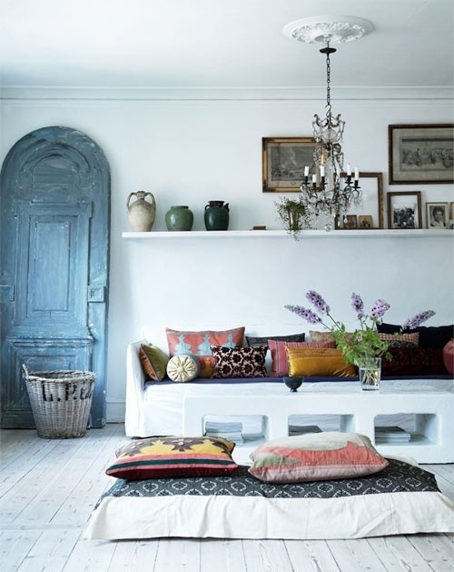 a white Moroccan living room with colorful pillows, teaware, a vintage door and accessories