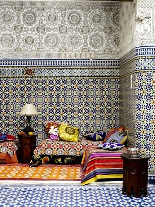 a fully mosaic tile lviing room with a colorful sofa and pillows and carved tables will make your jaw drop