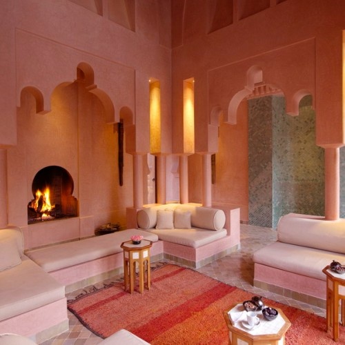 a bright Moroccan living room with cutout niches, a colorful rug and hexagonal coffee tables