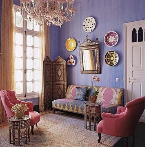 a colorful Moroccan living room with bright furniture, an ornate screen and decorative plates on the wall