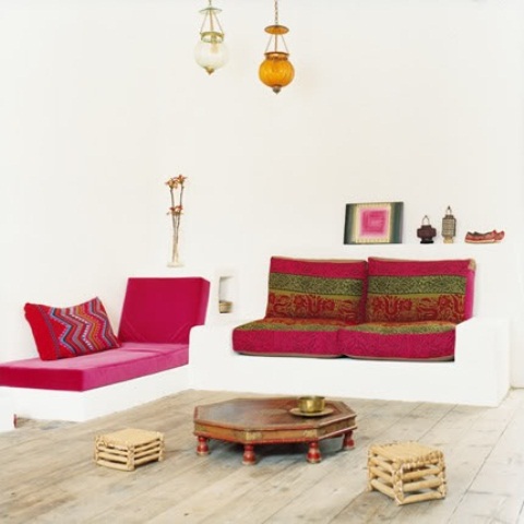 a neutral Moroccan living room done with colorful printed textiles, pendant lamps and low tables