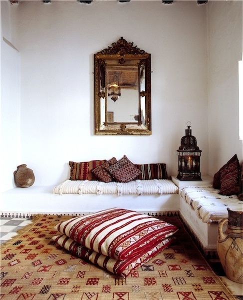 a neutral Moroccan living room with colorful and patterned pillows, a mirror and a lantern